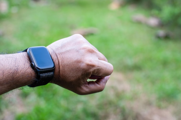 Smartwatch preto e bracelete de relógio no pulso esquerdo do homem espaço de cópia à direita para entrada de texto É uma foto de close com um fundo desfocado