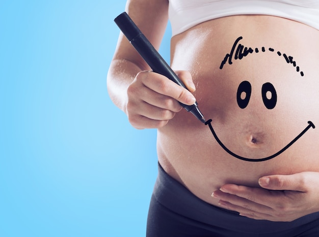 Smiley dibujado en el estómago de una mujer embarazada