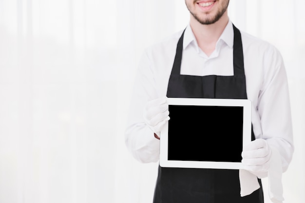 Foto smiley-diener, der eine tablette mit modell hält