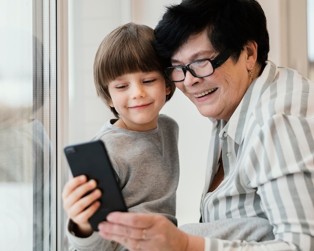 Foto smiley-enkel und großmutter, die smartphone zusammen betrachten