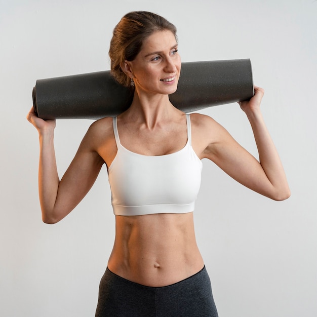 Foto smiley-frau, die yogamatte hält