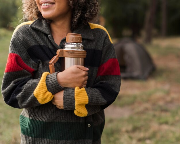 Foto smiley frau im freien camping hält thermoskanne