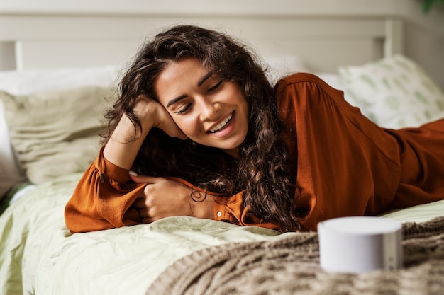 Smiley-Frau mit mittlerem Schuss, die im Bett liegt