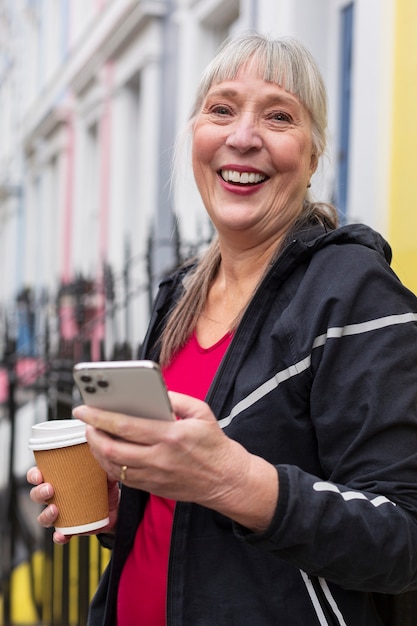 Smiley-Frau mit mittlerem Schuss, die Smartphone hält