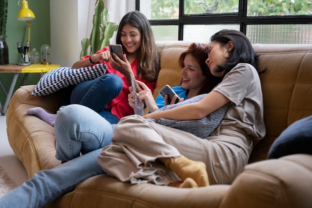 Smiley-Frauen der Seitenansicht, die auf Couch sitzen