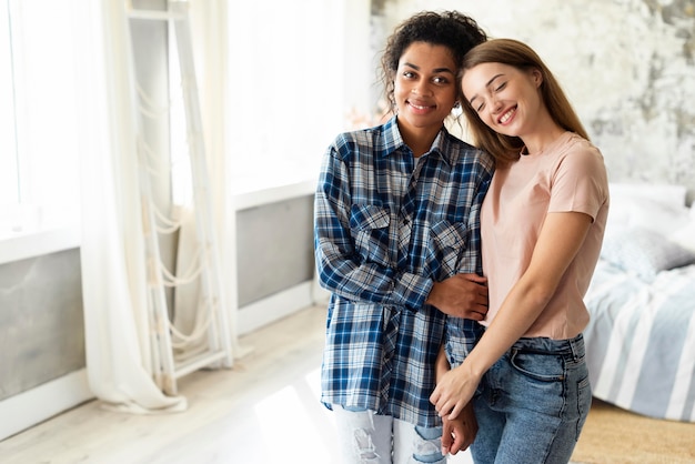 Foto smiley-freundinnen, die zusammen zu hause mit kopierraum aufwerfen