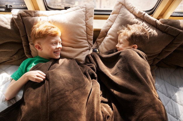 Foto smiley-kinder mit hohem winkel, die im bett liegen