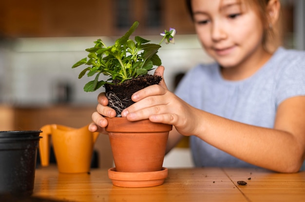 Smiley kleines Mädchen, das Blumen in Topf zu Hause pflanzt