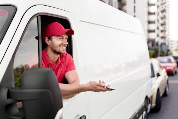 Foto smiley-lieferbote im auto mit handy