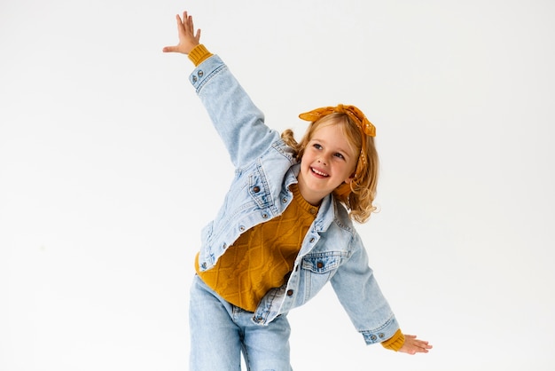 Foto smiley-mädchen der vorderansicht, das im studio aufwirft