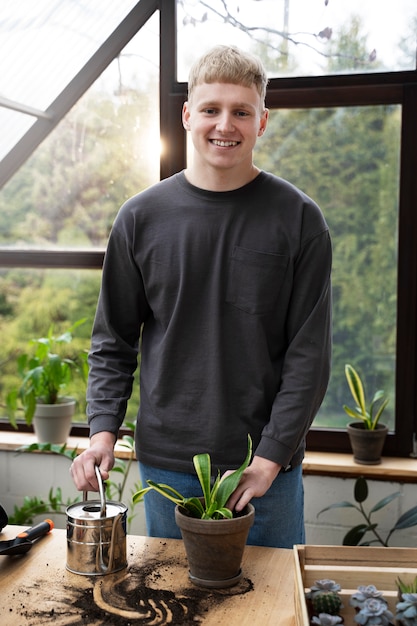 Foto smiley-mann mit mittlerem schuss, der eine pflanze umpflanzt