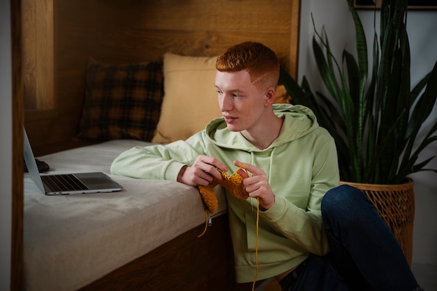 Foto smiley-mann mit mittlerem schuss, der zu hause strickt