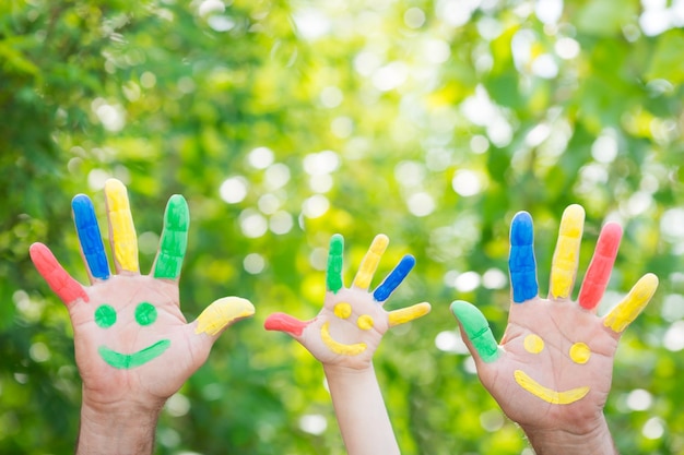 Smiley en las manos contra el fondo verde de la primavera Familia divirtiéndose al aire libre