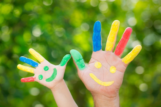 Foto smiley en las manos contra el fondo verde de la primavera padre e hijo divirtiéndose al aire libre