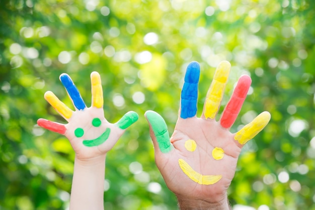 Smiley en las manos contra el fondo verde de la primavera Padre e hijo divirtiéndose al aire libre