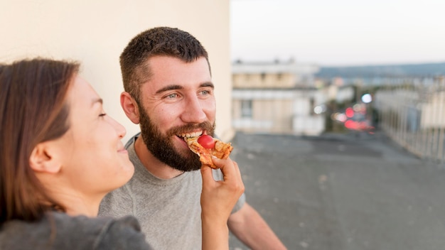 Smiley-Paar, das draußen Pizza isst