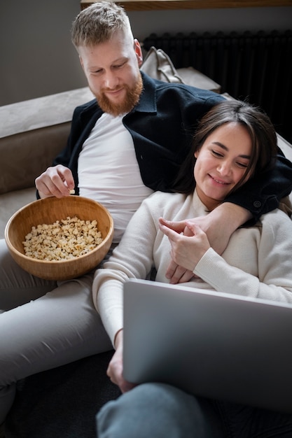 Smiley-Paar mit mittlerer Aufnahme, das sich einen Film mit Popcorn ansieht