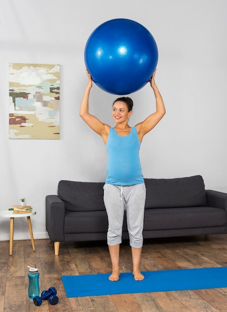 Foto smiley schwangere frau zu hause training auf übungsmatte mit ball