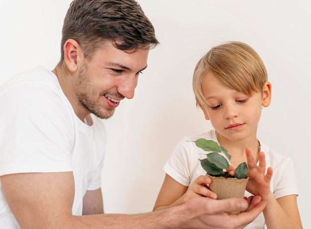 Foto smiley vater und sohn halten topf der pflanze