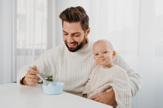 Foto smiley vater zur fütterungszeit mit seinem baby