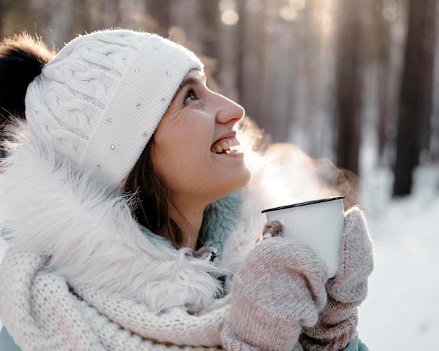 Smileyfrau draußen im Winter, die eine Tasse Tee hält