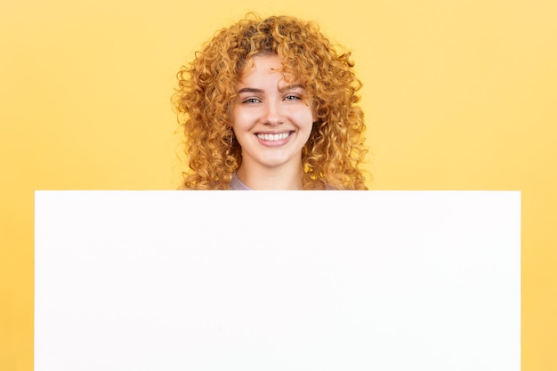 Smileyfrau mit dem gelockten Haar, das eine Leerplatte anhält