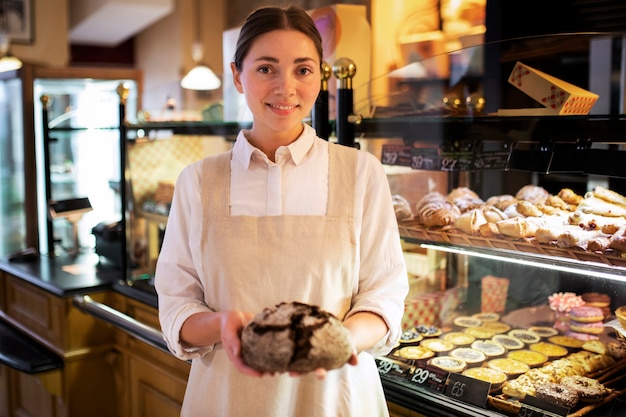 Foto smileyfrau mit mittlerer aufnahme in der bäckerei