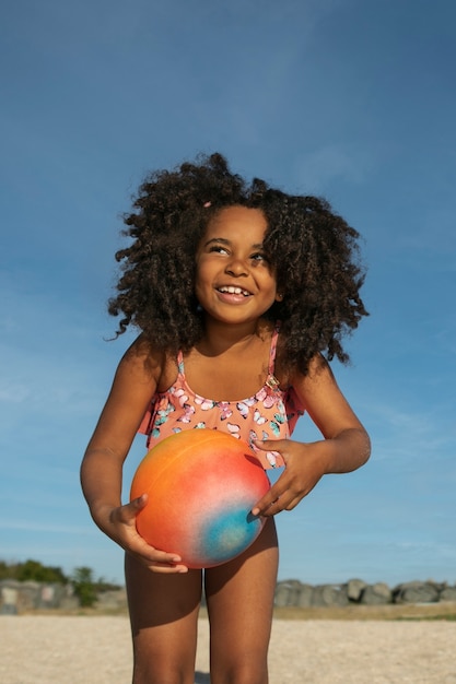 Smileymädchen am Strand, der niedrigen Winkel des Balls hält