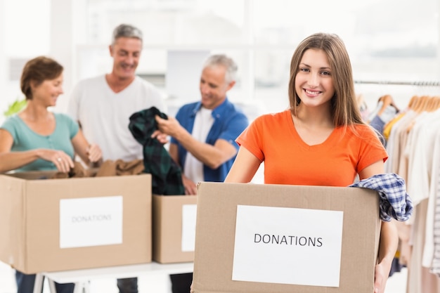 Smiling casual businesswoman holding donation box