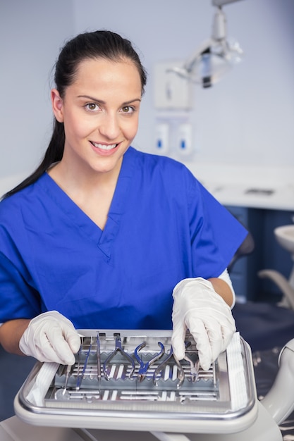 Smiling dentista pegando uma ferramenta na bandeja