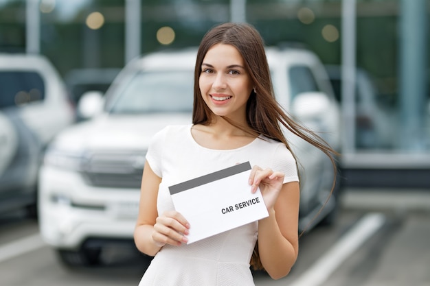 Smilling Frau mit Vereinbarung Autoservice auf Hintergrund des Autohauses