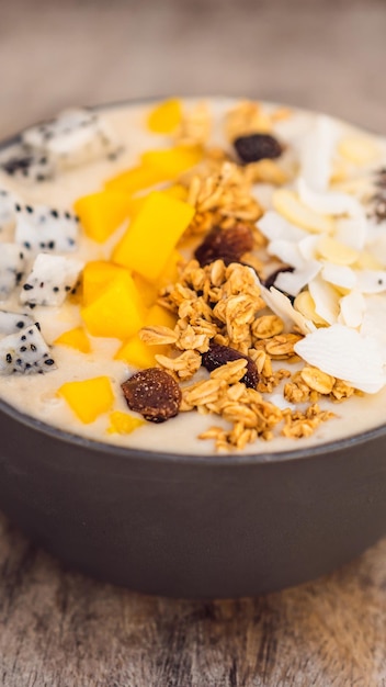 Smoothie Bowls mit Mango-Bananen-Müsli, geriebener Kokosnuss, Drachenfrucht, Chiasamen und Minze