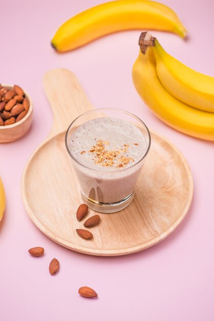 Smoothie de banana fresca em um copo em fundo rosa