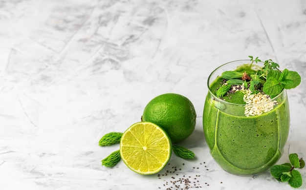 Smoothie de espinafre com sementes de banana, limão, chia e gergelim e microgreens em um copo de vidro