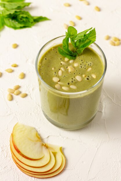 Smoothie de frutas verdes misturadas em vidro com pinhões