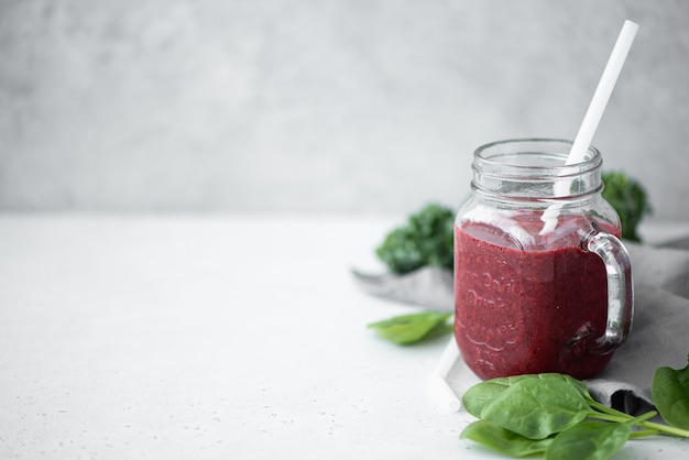 Smoothie de frutas vermelhas com espinafre e sementes de chia em uma caneca de vidro