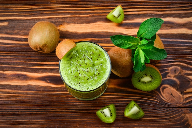 Smoothie de kiwi fresco e saudável em vidro com fundo de madeira