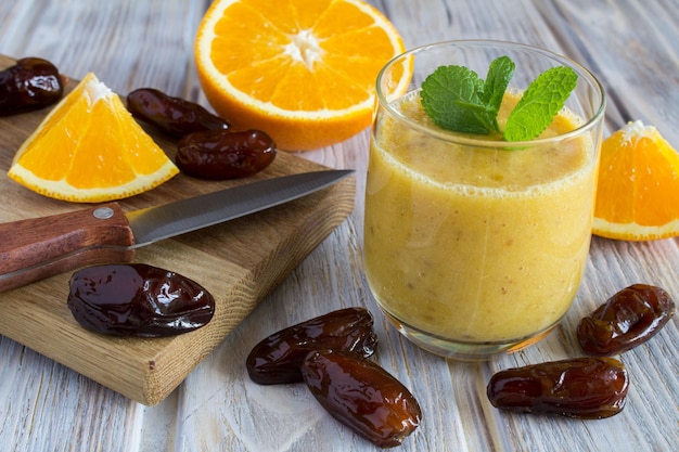 Smoothie de laranja e datas no fundo de madeira marrom claro