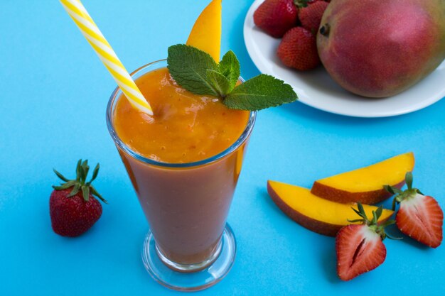 Smoothie de manga e morango no fundo azul