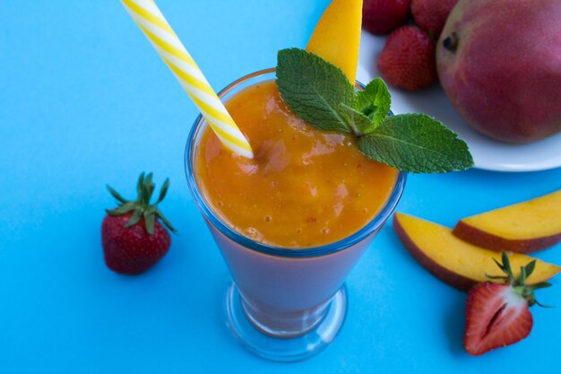 Smoothie de manga e morango no fundo azul