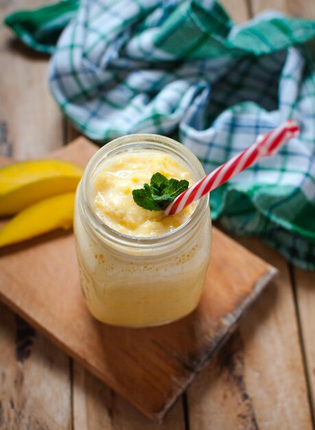 Foto smoothie de manga em um frasco em uma mesa de madeira