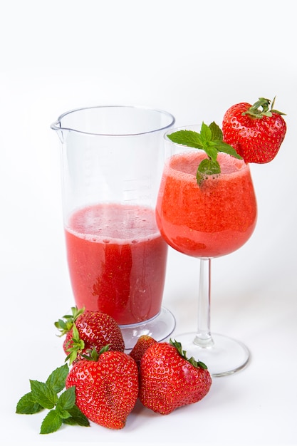 Smoothie de morango em um copo com uma perna alta, decorado com morangos e hortelã em branco