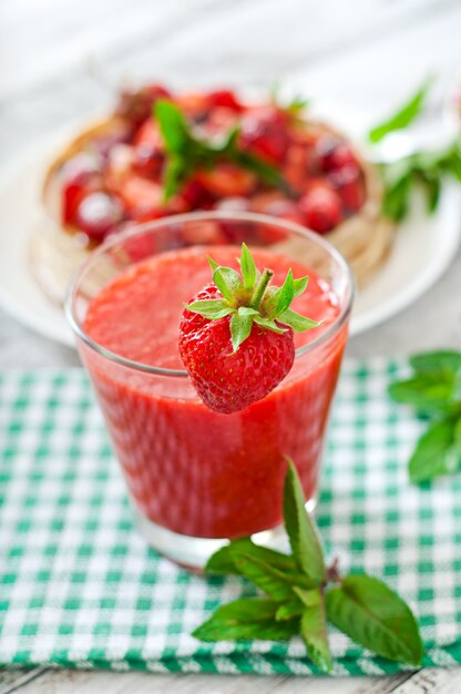 Smoothie de morango em vidro e hortelã folhas sobre um fundo de madeira em estilo rústico