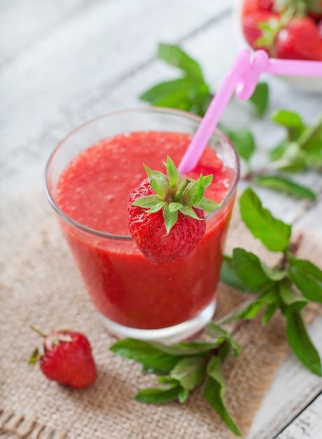 Smoothie de morango em vidro e hortelã folhas sobre uma superfície de madeira em estilo rústico