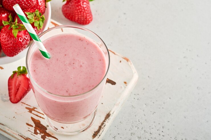 Smoothie de morango ou milkshake com frutas e hortelã em copo alto sobre fundo cinza claro. Conceito orgânico de shake, milk-shake e refresco de bebida de verão. Lugar para texto.