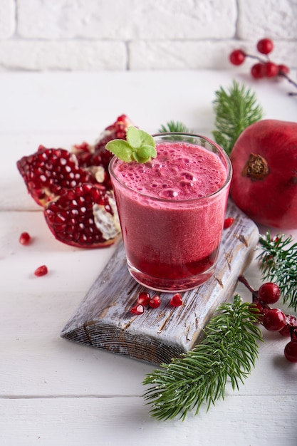 Smoothie de romã em um copo com ramos de abeto e decoração de Natal