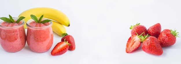 Smoothie mit Erdbeere und Banane im Glasgefäß und reife Erdbeere auf dem weißen Hintergrund Platz kopieren Banner