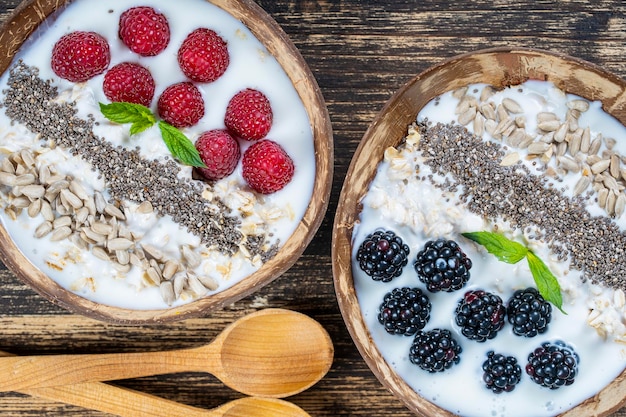 Smoothie na tigela de coco com amoras framboesas aveia sementes de girassol e sementes de chia no café da manhã close-up O conceito de superalimento de alimentação saudável