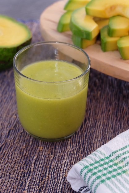 Smoothie ou suco de abacate com uma fatia de abacate como fundo