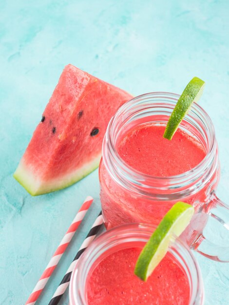 Smoothie de sandía con lima y menta en un frasco de mampostería sobre un fondo de madera blanca